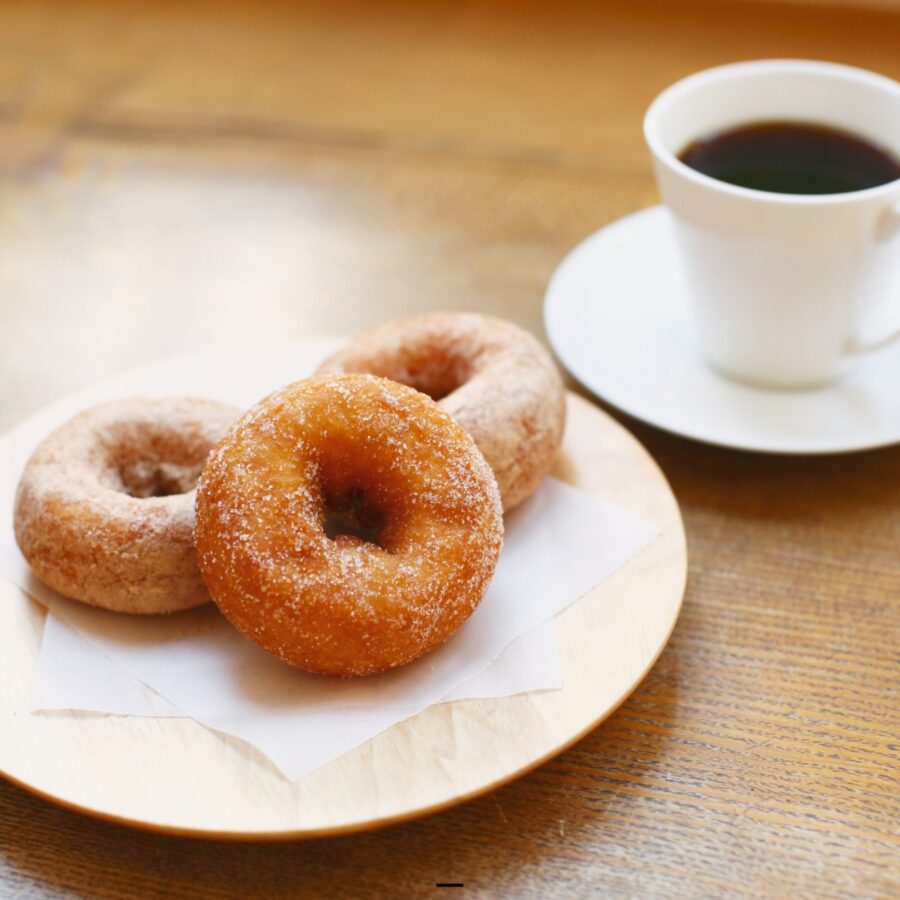 Three keto donuts on a wooden platform with a cup of coffee next to them - 22