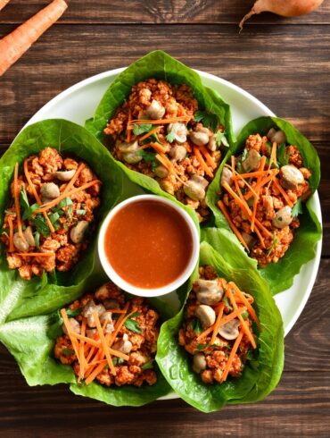 Korean Lettuce Wraps on a plate with a dipping sauce in the middle