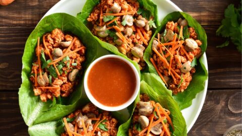 Korean Lettuce Wraps on a plate with a dipping sauce in the middle