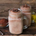 two coffee smoothies in mason jars on a wooden surface