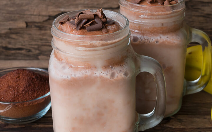 two coffee smoothies in mason jars on a wooden surface
