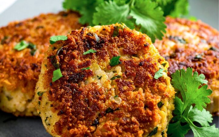 Close up image of Crab cakes on a plate with herb garnish