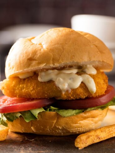 Fried Frish Sandwich on a rustic surface with french fries