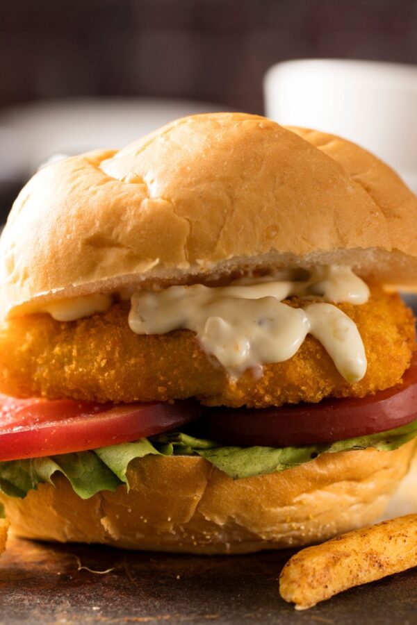 Fried Frish Sandwich on a rustic surface with french fries