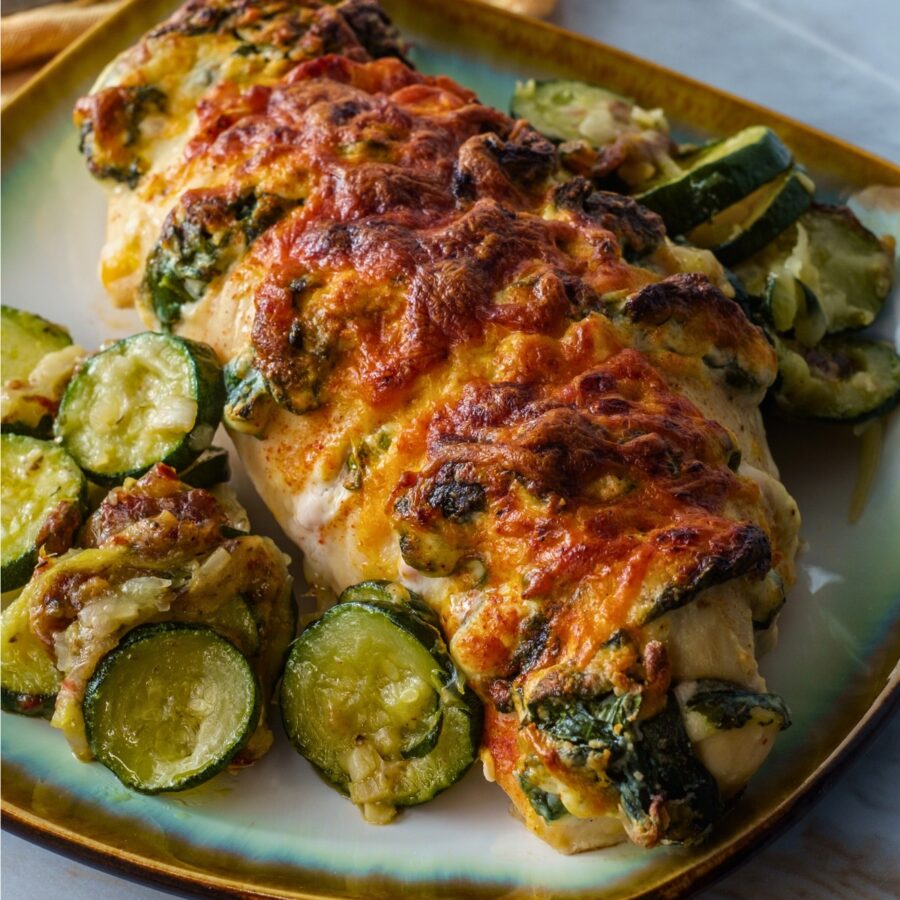 Overhead image of hasselback chicken on a plate with a vegetable side dish