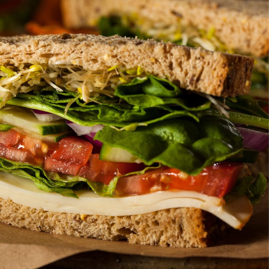 Hummus and Veggie Sandwich cut in half on parchment paper