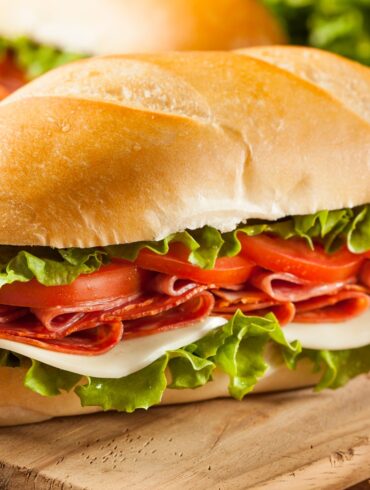 Two Italian Sub Sandwiches on a wooden cutting board