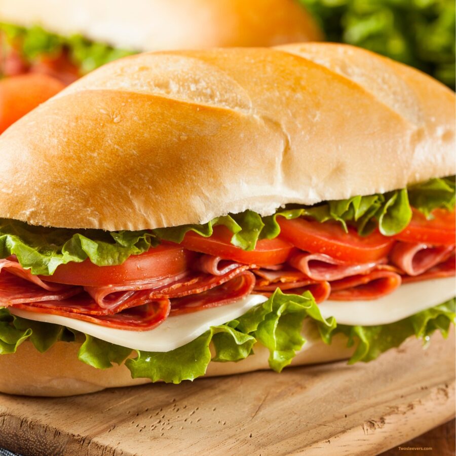 Two Italian Sub Sandwiches on a wooden cutting board
