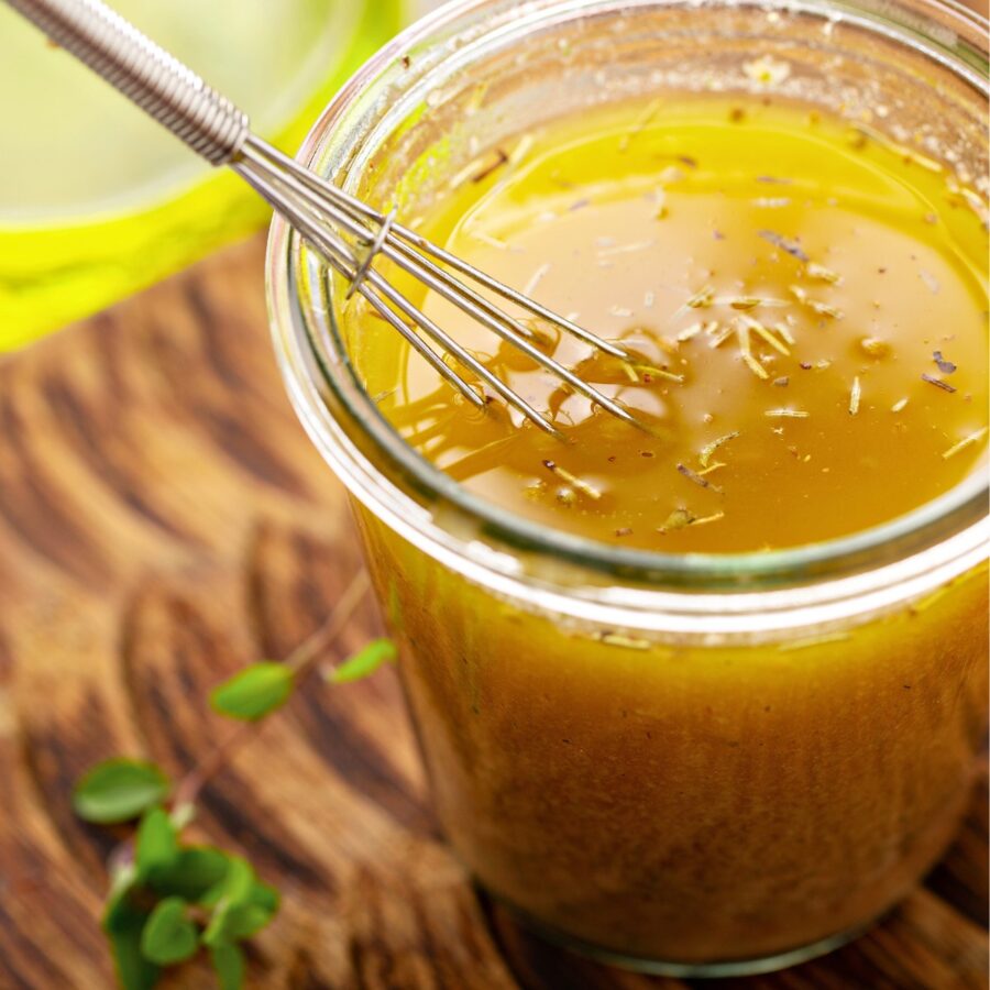 Lemon Vinaigrette in a glass jar with a small whisk