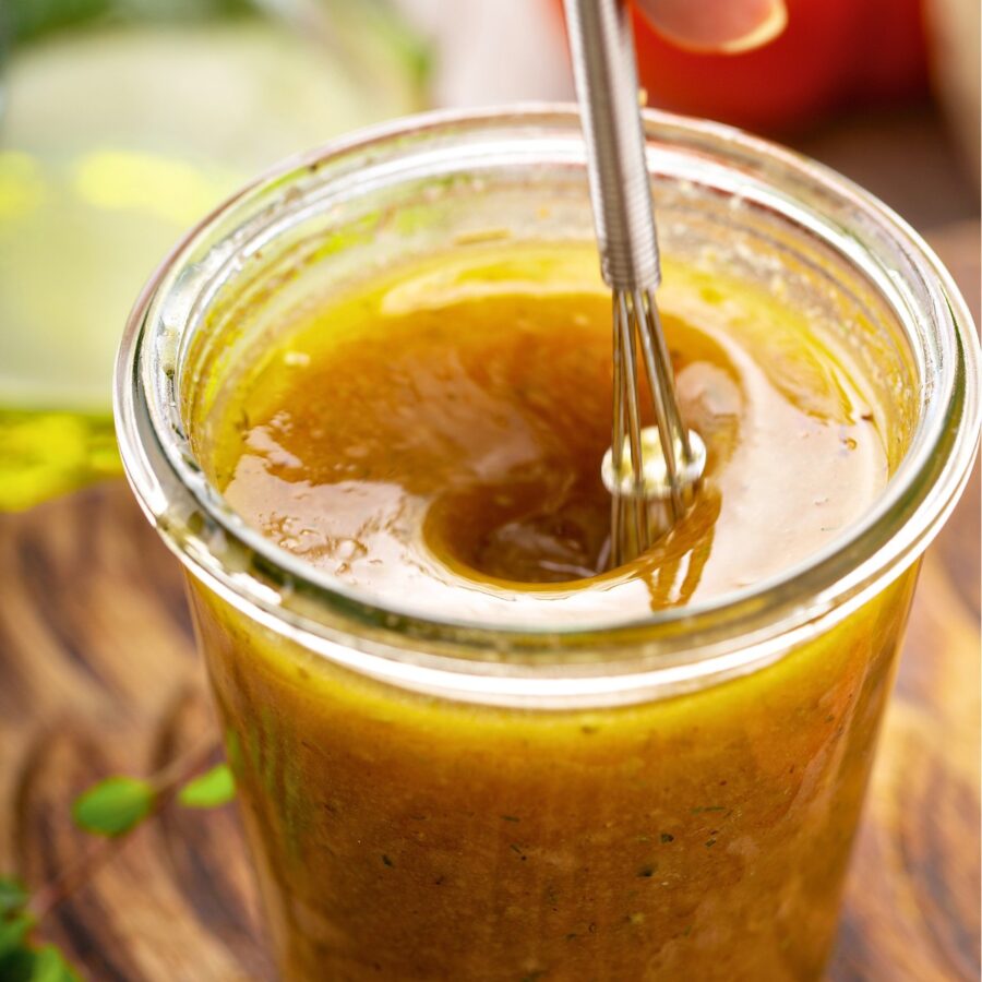 Close up image of Lemon Vinaigrette in a glass jar with a small whisk