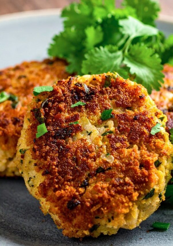 Close up image of Crab cakes on a plate with herb garnish