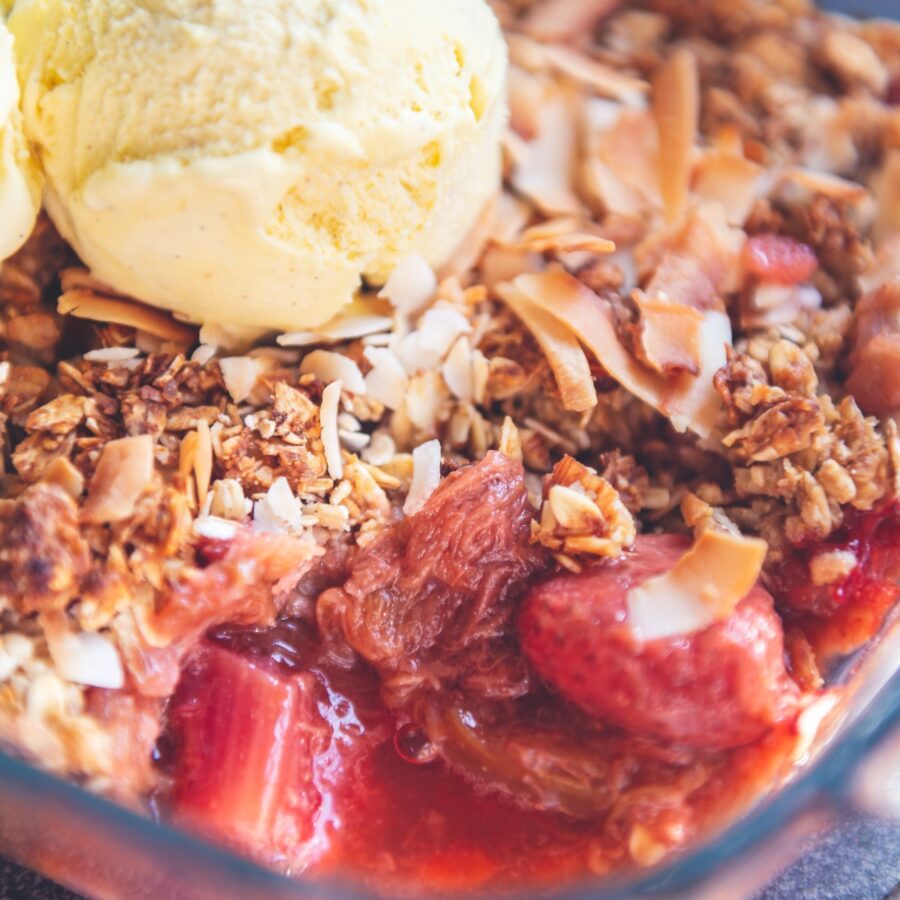Close up image of strawberry rhubarb crisp with a scoop of ice cream on top