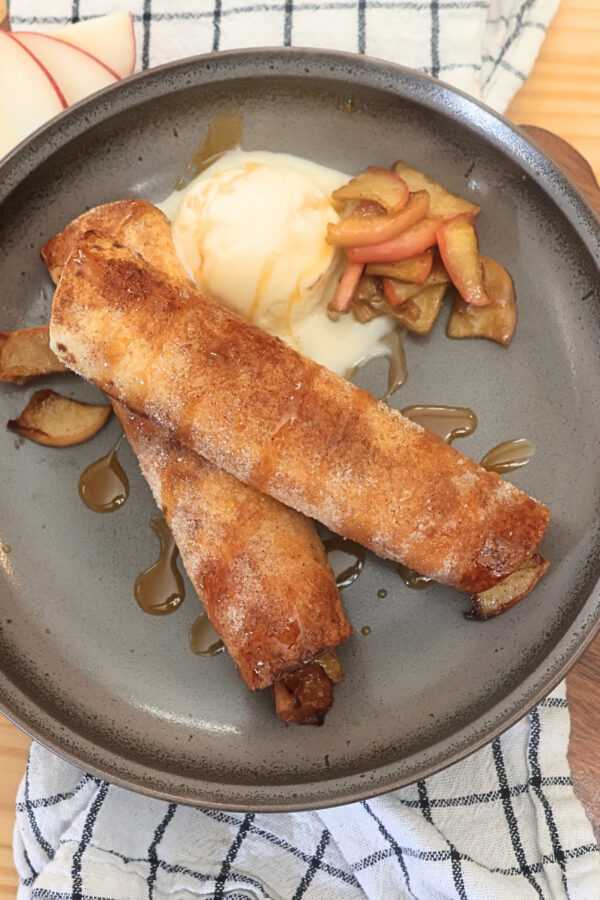 Overhead image of two Air Fryer Apple Pie Taquitos on a plate with ice cream
