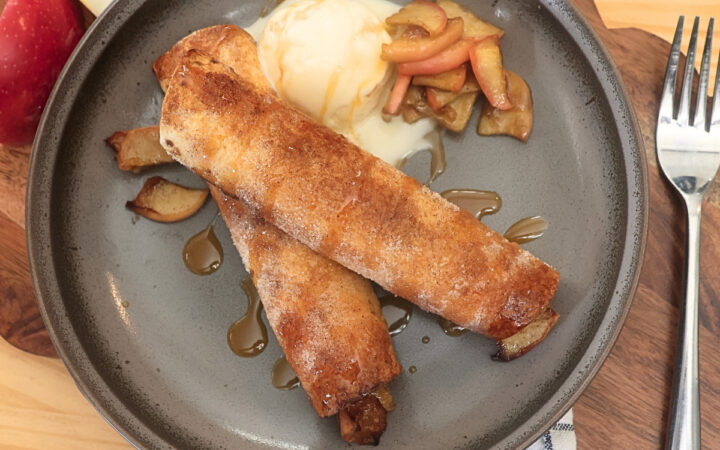 Overhead image of two Air Fryer Apple Pie Taquitos on a plate with ice cream