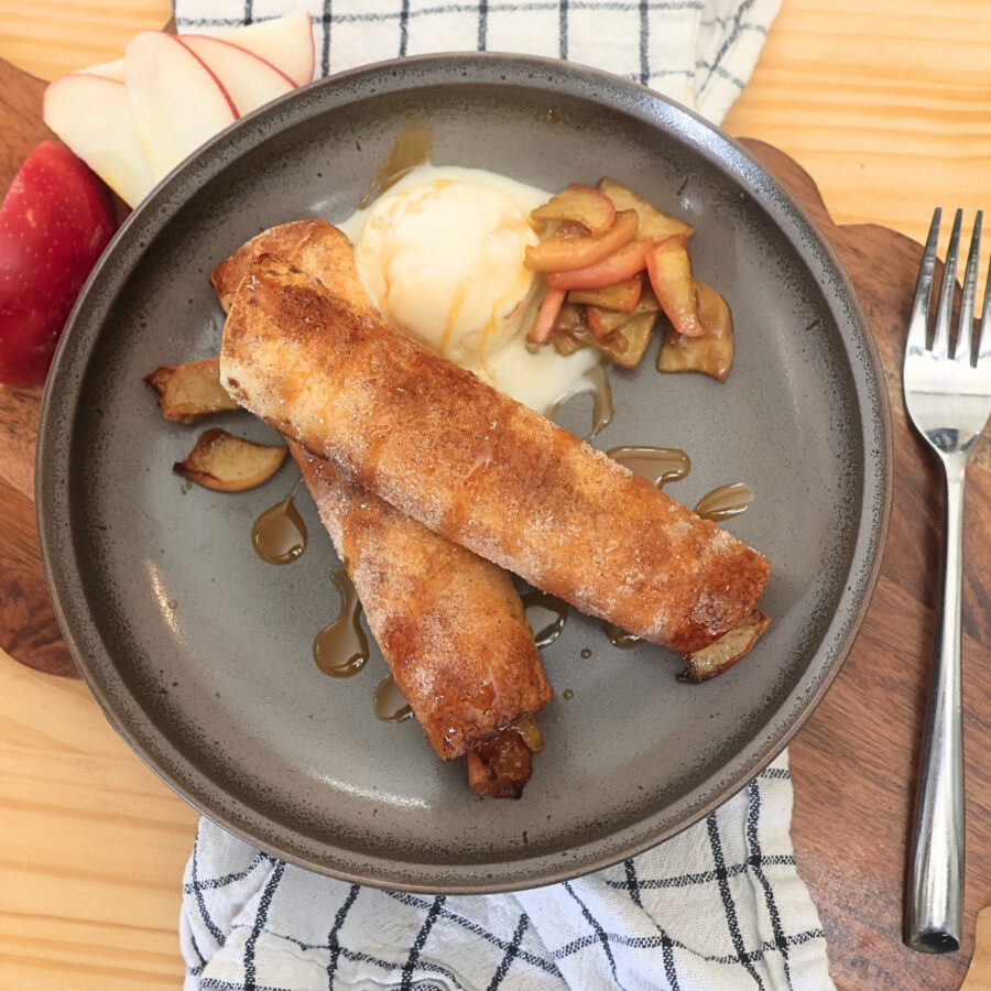Overhead image of two Air Fryer Apple Pie Taquitos on a plate with ice cream