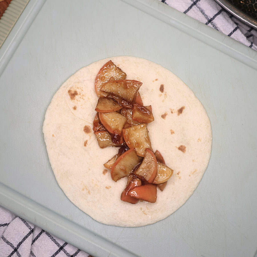 A small flour tortilla with cooked cinnamon sugar apples on it