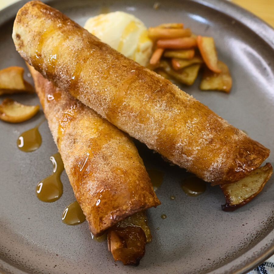 Close up image of air fryer apple pie taquitos on a plate with ice cream