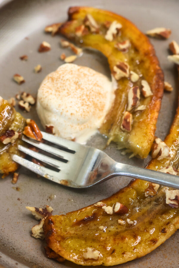 Close up image of air fryer carmelized bananas on a plate with a bite on a fork