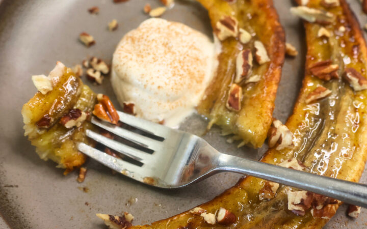 Close up image of air fryer carmelized bananas on a plate with a bite on a fork