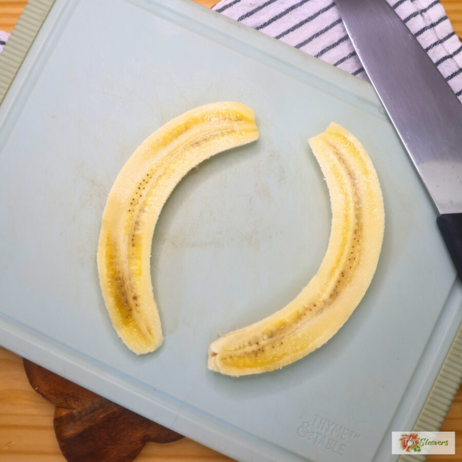 A banana cut in half lengthwise on a cutting board