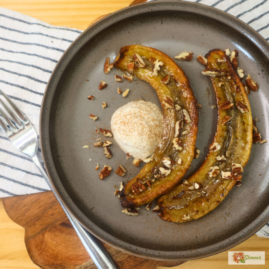 Overhead image of air fryer caramelized bananas on a plate with whipped topping and chopped pecans
