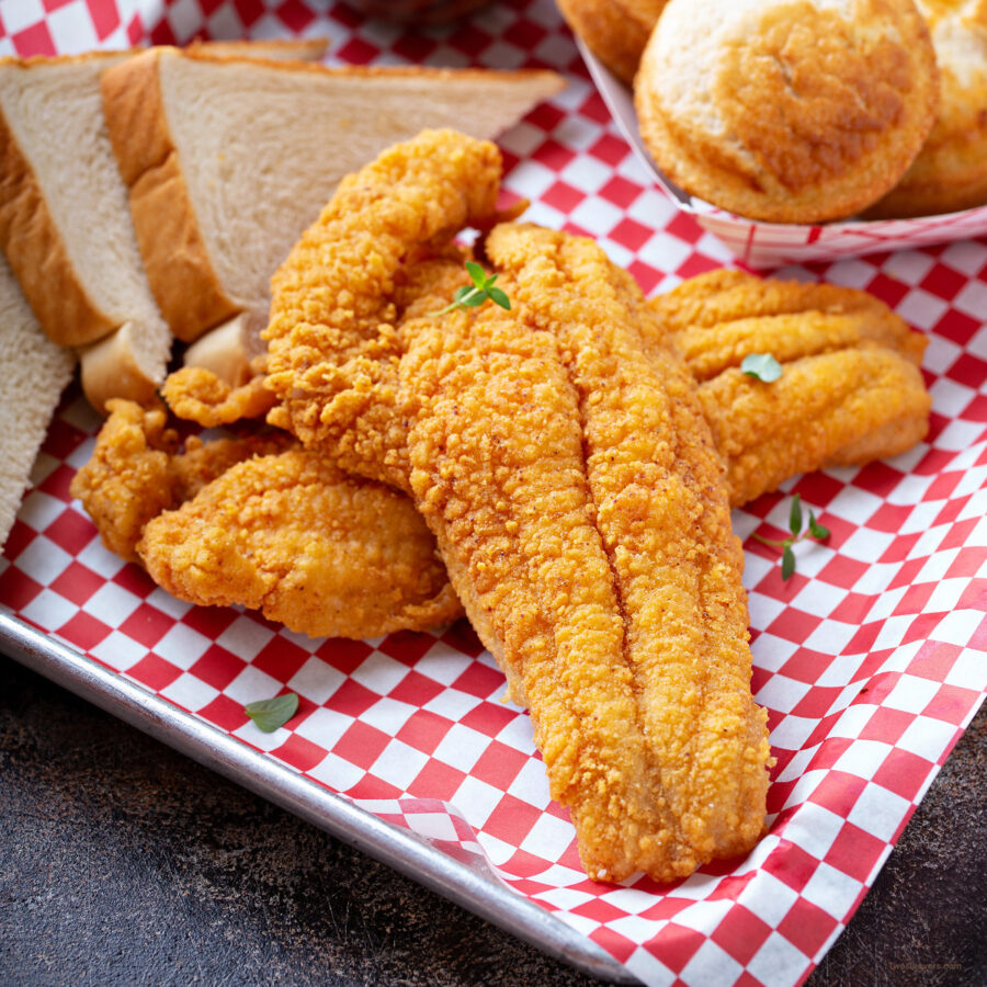 A tray with air fryer catfish with a checked paper under it