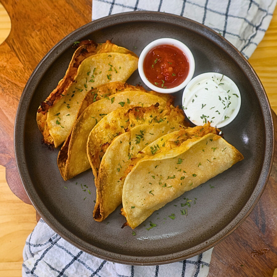 Overhead image of Air Fryer Crispy Chicken Tacos on a plate with salsa and sour cream