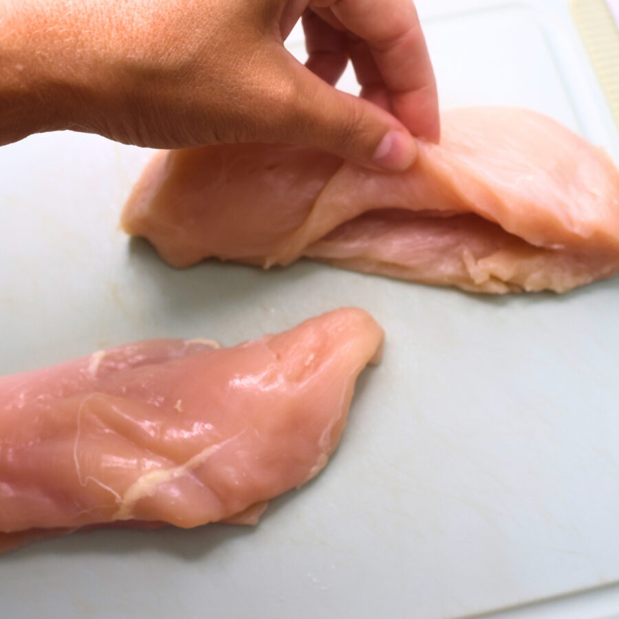Two chicken breasts on a cutting board with a pocket cut in the middles