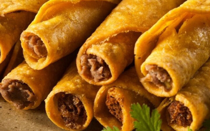 air fryer taquitos stacked on a plate with cilantro garnish