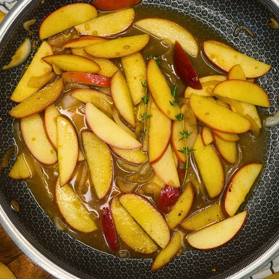 Sliced apples and caramelized onions in a skillet wi th pan sauce