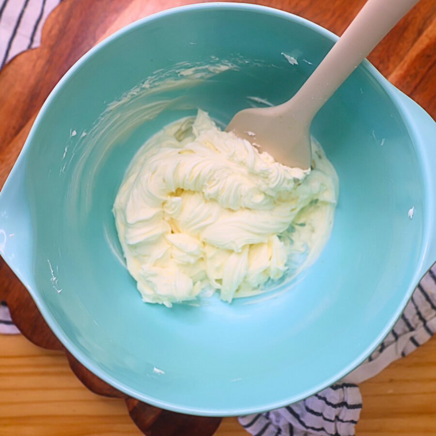 Softened cream cheese in a blue bowl with a spatula