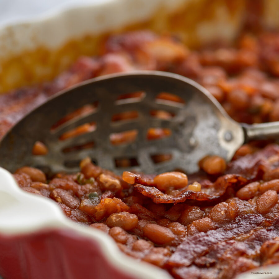 Close up image of Baked Beans and Bacon being served with a metal spoon