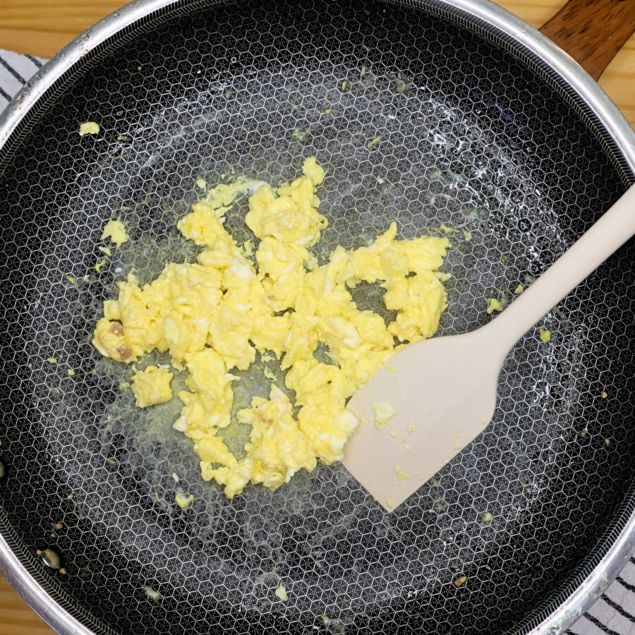 Scrambled eggs in a skillet with a silicone spatula