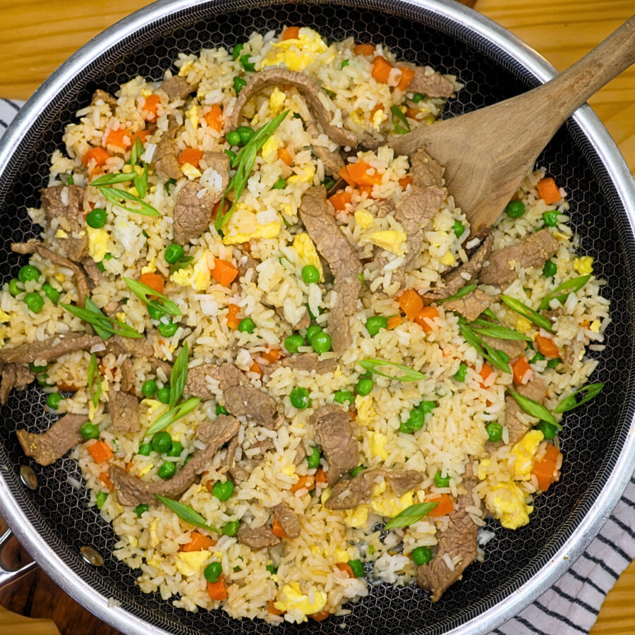 Beef fried rice in a skillet garnished with green onion