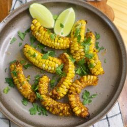 Caju Overhead image of Cajun Butter Corn Ribs with parsley and lime wedges