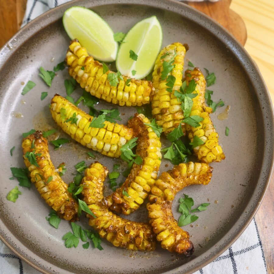 Overhead image of Cajun Butter Corn Ribs with parsley and lime wedges