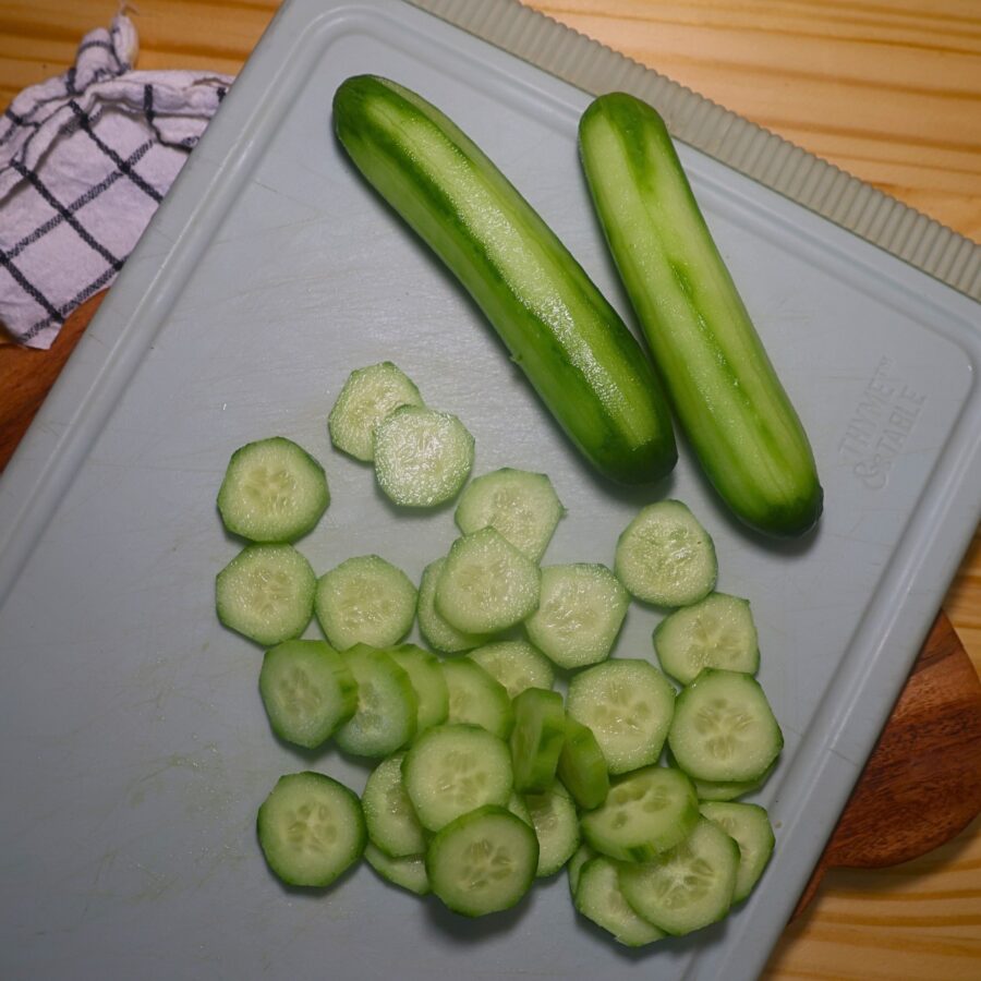 Cucumbers on a cutting board with some sliced into rounds