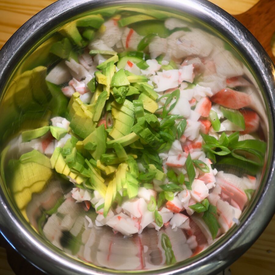 Chopped veggies and imitation crab meat in a metal bowl