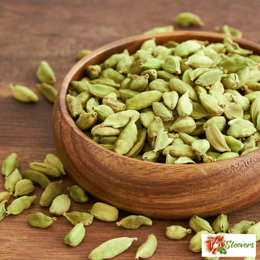 Cardamom in a wooden bowl with some scattered on the table