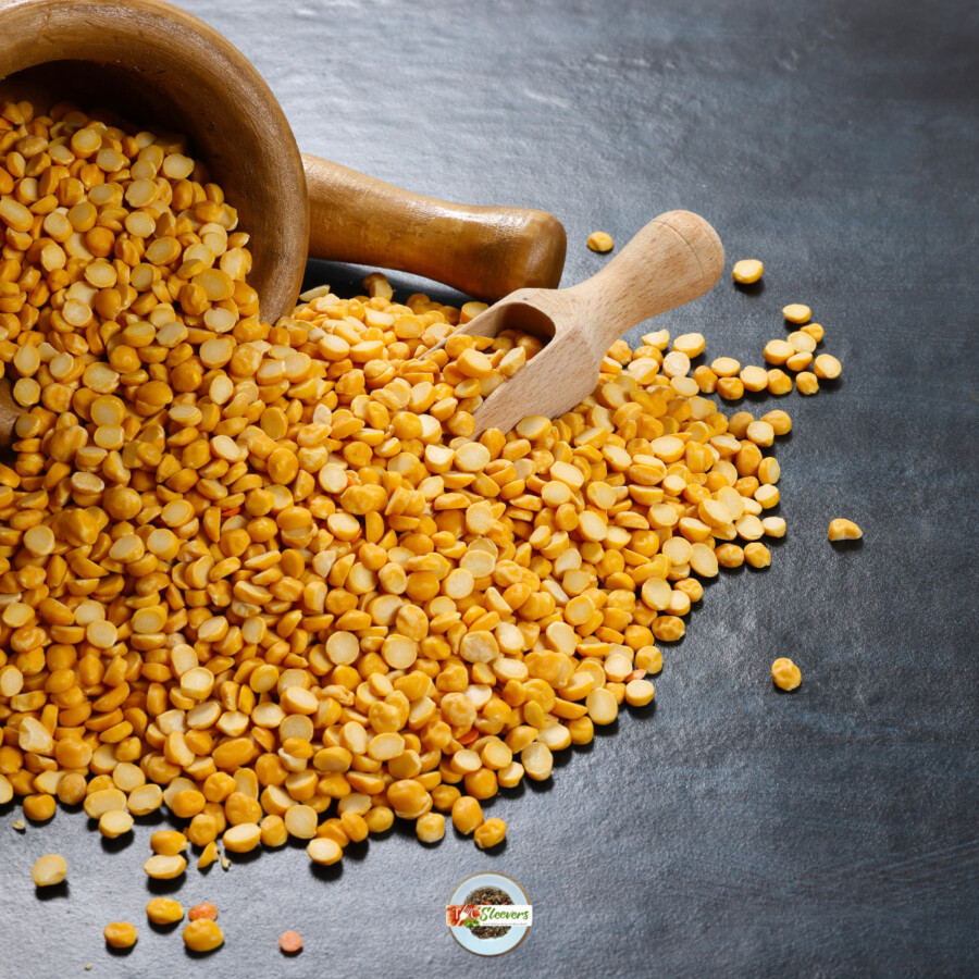 Chana dal pouring out of a bowl with a small wooden scoop