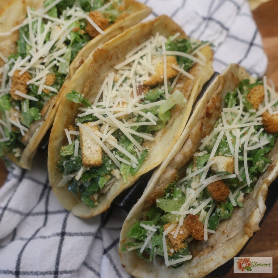 Three Chicken Caesar Smash Tacos in a taco holder over a checked cloth