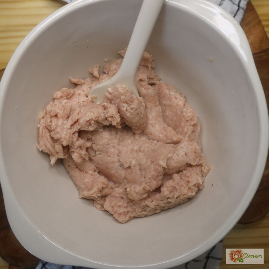 Seasoned uncooked ground chicken in a mixing bowl