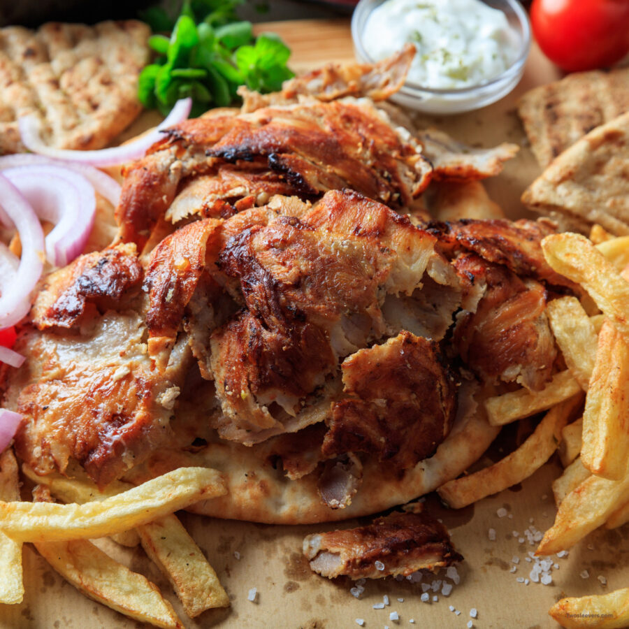 A Chicken Gyro being assembled on parchment paper