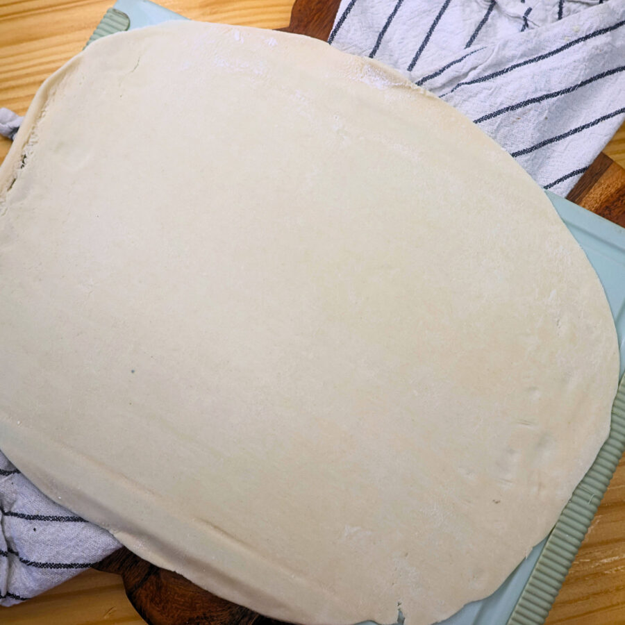 Uncooked pie crust stretched over a cutting board