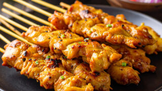 Close up image of Chicken Satay stacked on a plate