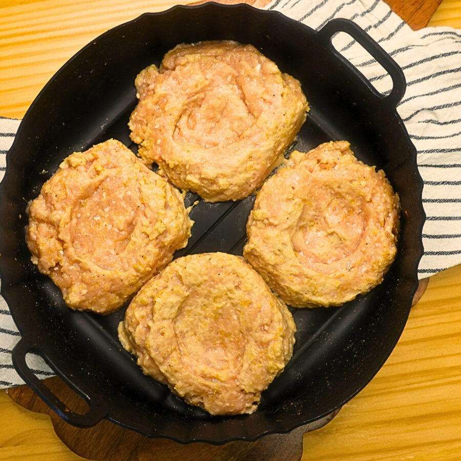 Uncooked chicken teriyaki burger patties in an air fryer basket