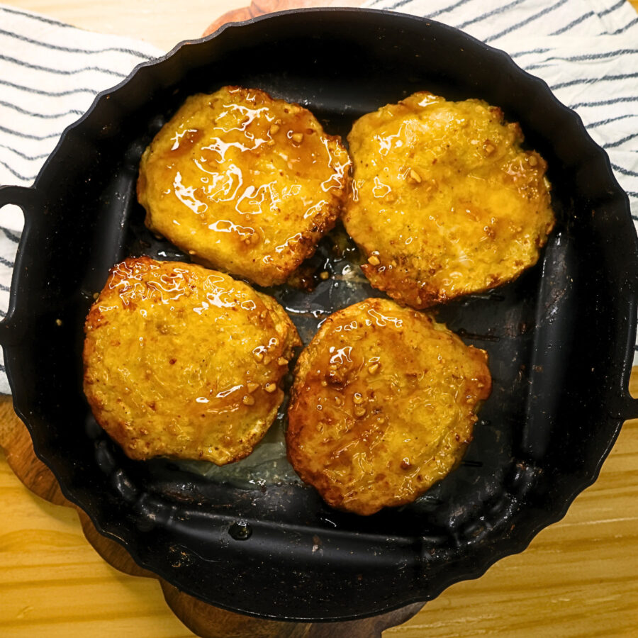 Cooked chicken teriyaki burger patties coated in teriyaki sauce in an air fryer basket