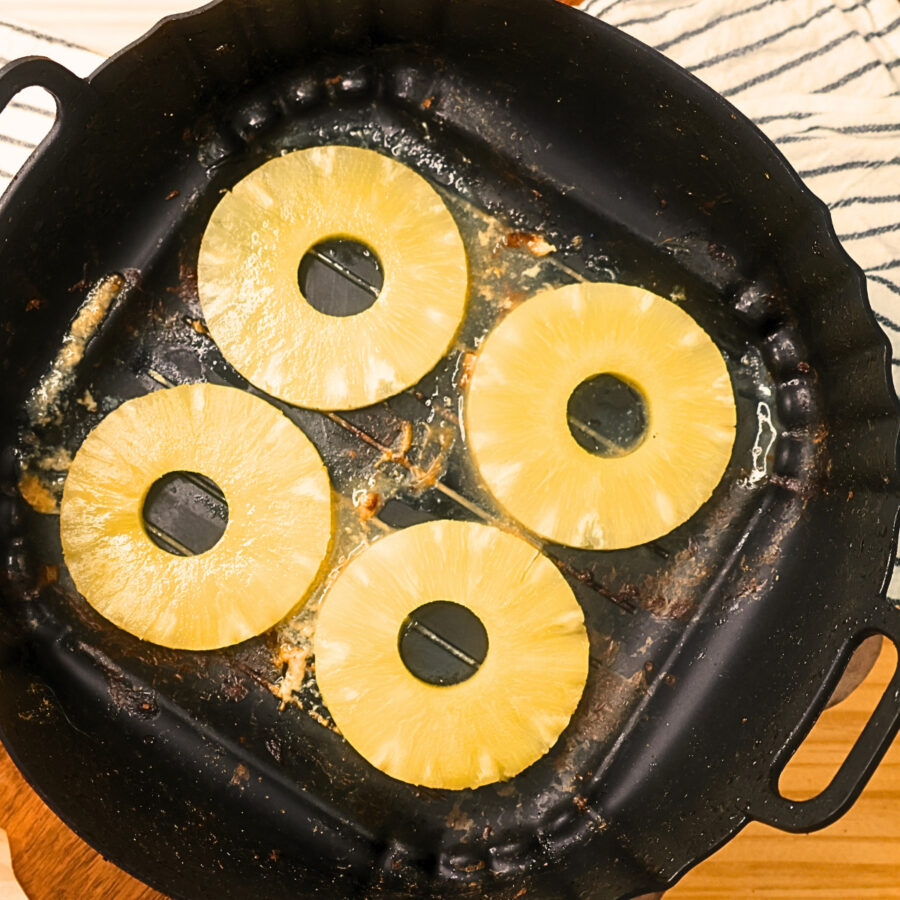 Four cooked pineapple slices in an air fryer basket