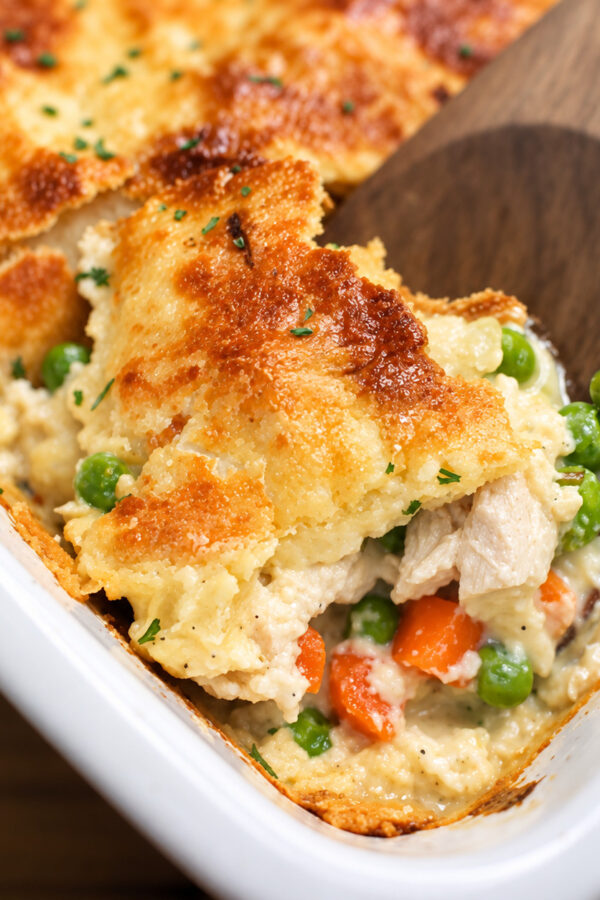 Close up image of chicken pot pie casserole being served with a wooden spoon