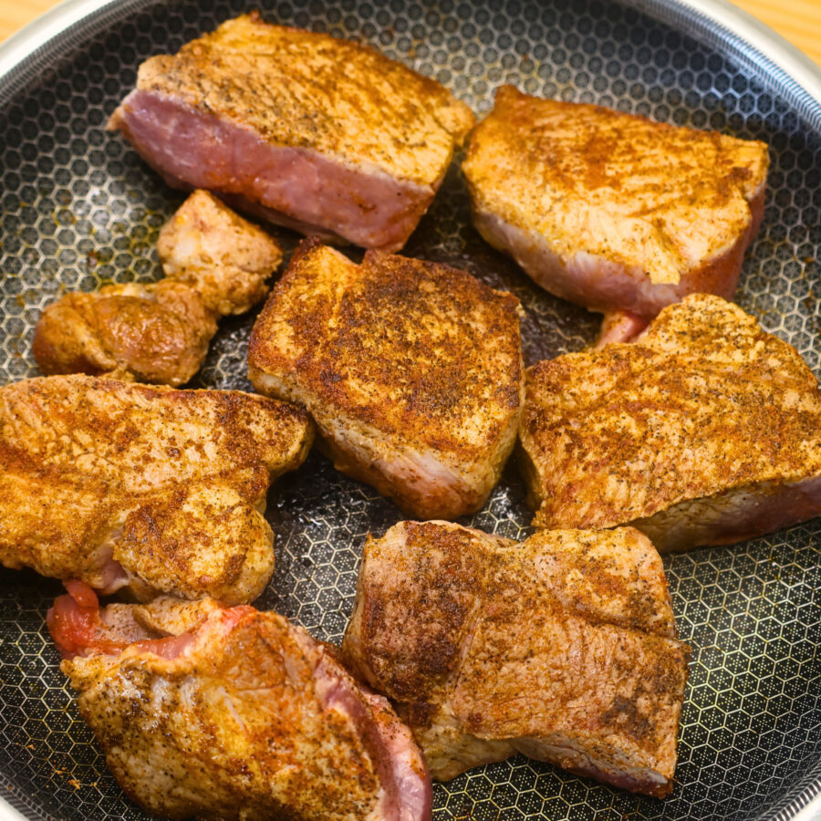 Chunks of seasoned pork roast browned in a skillet